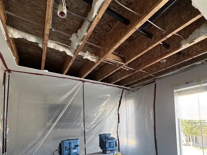 Ceiling opened to the joists with a dehumidifier running inside plastic containment